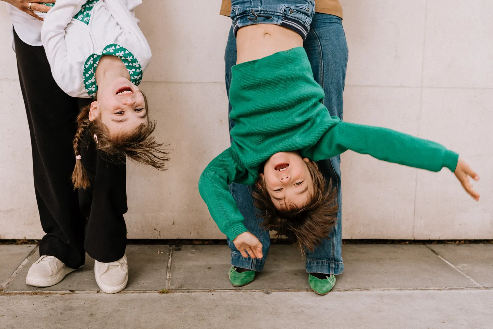 Deux enfants tenus la tête en bas éclatent de rire
