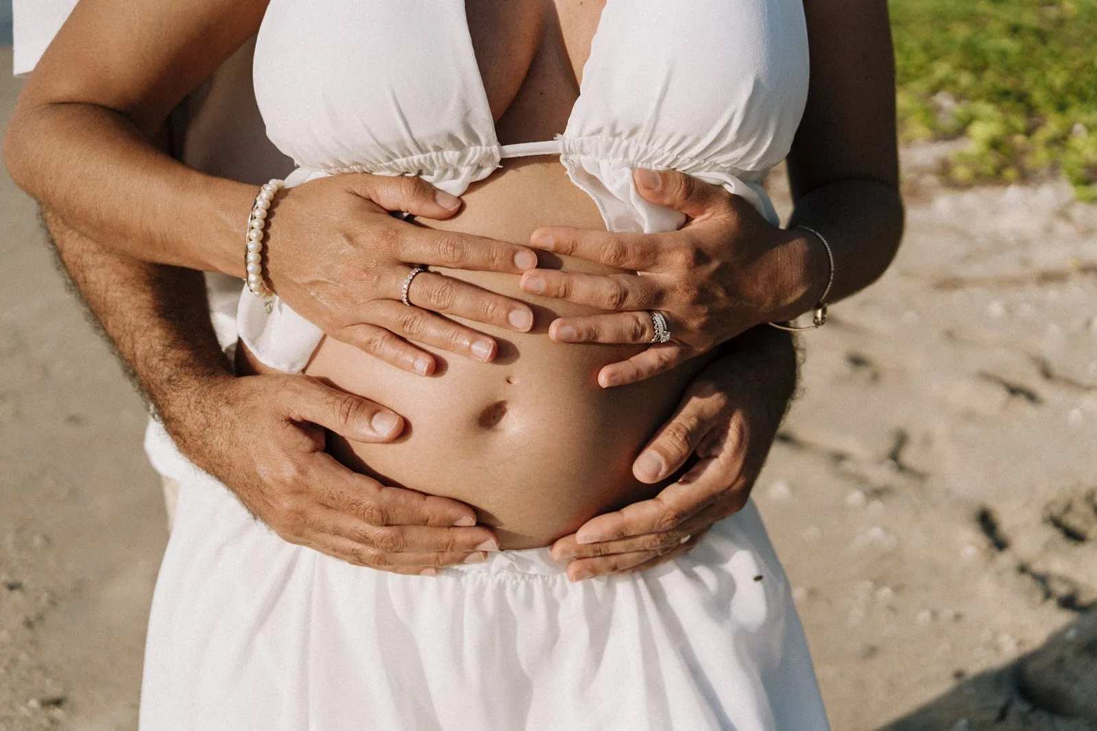 Les mains des futurs parents réunies sur le ventre arrondi