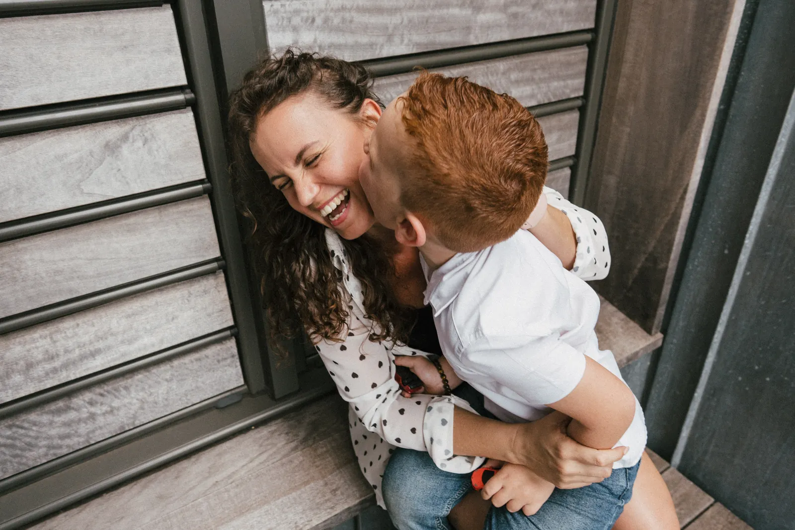 Une maman serre son fils contre elle en riant pendant qu'il lui fait un bisou